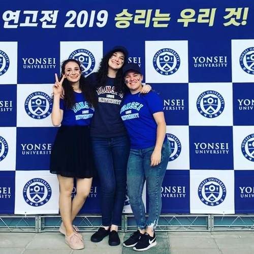 Three students standing in front of Yonsei University Billboard